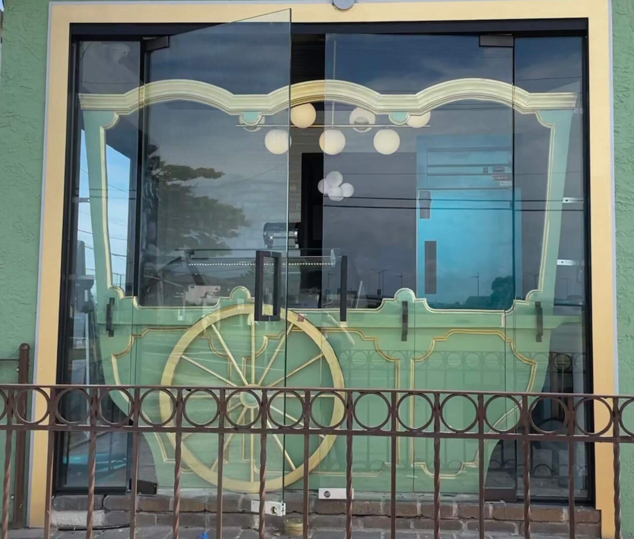 A green carriage is reflected in the window of an old building.