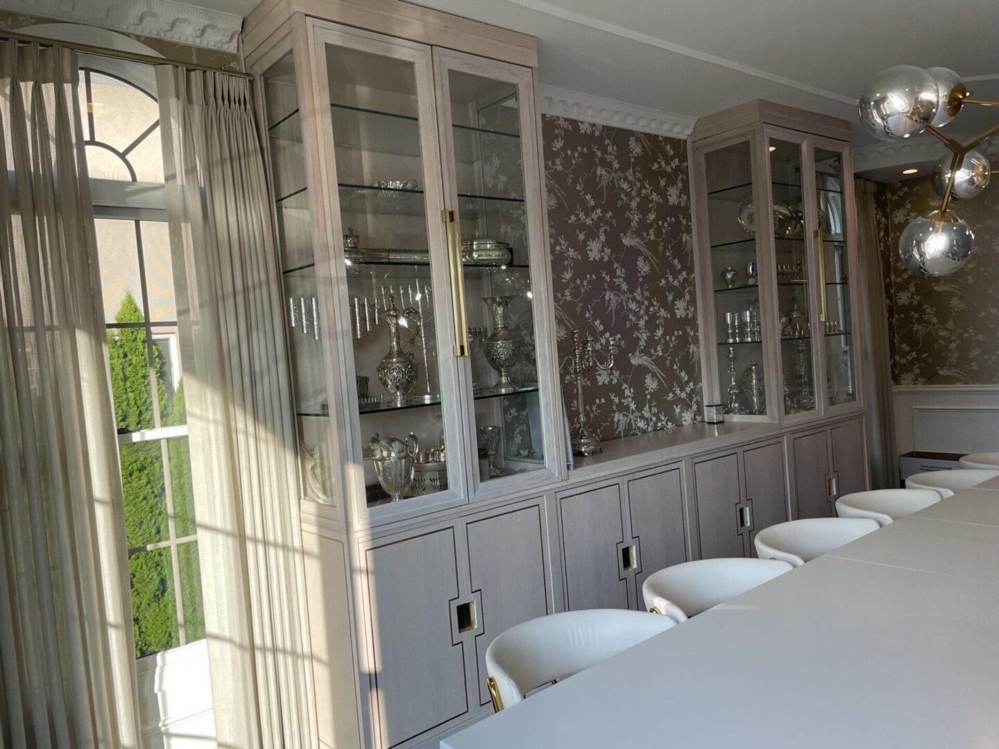 A large dining room with white chairs and glass cabinets.