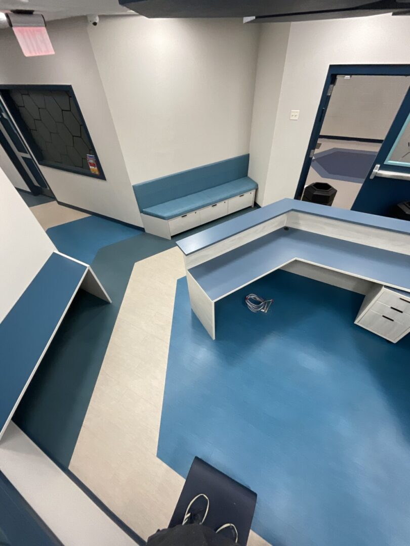 A view of a room with blue floors and a desk